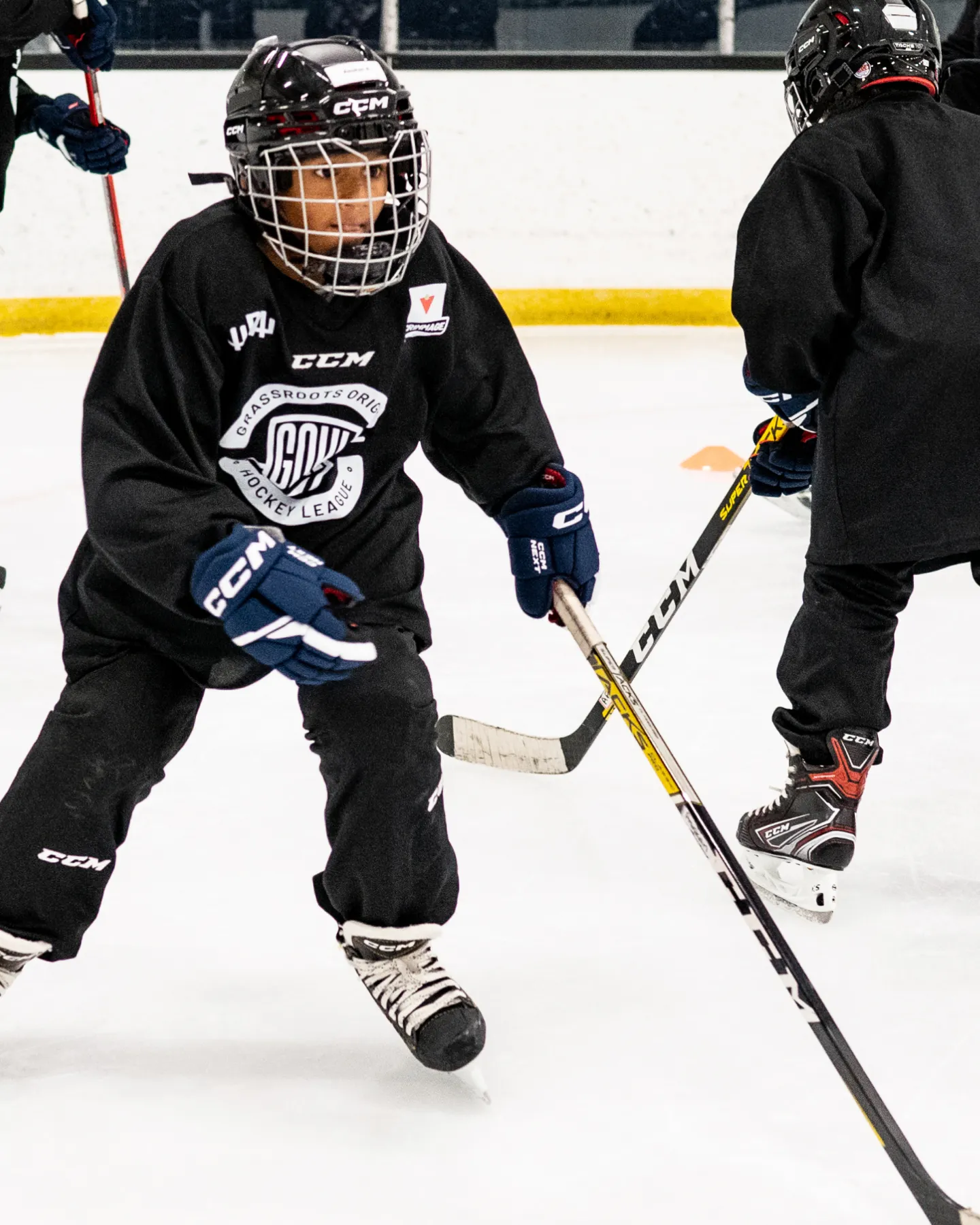 Enthusiastic young hockey player skillfully maneuvering on indoor ice rink during a lively game.
